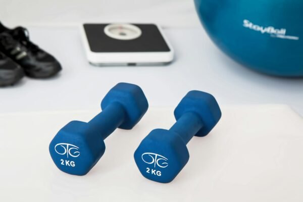 Blue dumbbells placed on a white surface with fitness equipment in the background.